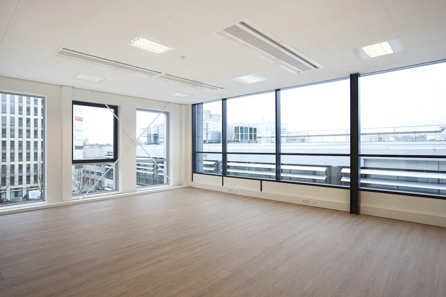 Lichte, lege kantoorruimte met houten vloer en grote ramen aan de De Boelelaan.